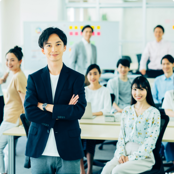 男性が腕を組み、他の人は椅子に座っている写真